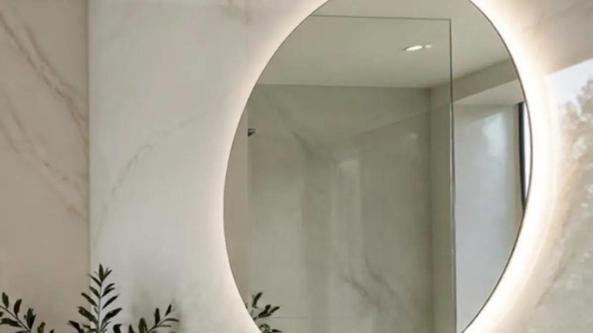 Espejo LED redondo con luz perimetral en un baño